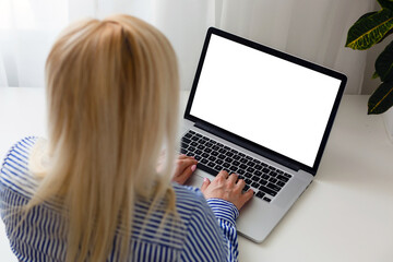 Wall Mural - Female hands typing on a laptop keyboard with isolated screen in a white room on a desk