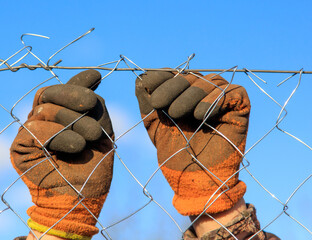 A man sets a metal mesh on the fence.