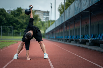 Wall Mural - young athlete has workout and doing sport exercises with kettlebell outdoor