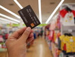 © Chanonnat - hand holding creadit card with blurred supermarket background.