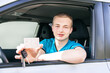 Car driver. Caucasian teen boy showing driver license, new car key and car.