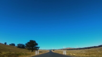 Wall Mural - driver’s view of the capital wind farm showing large wind turbines located along a countryside road 