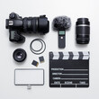 © Di Studio - videography and photography equipment - top view of modern dslr camera, lenses, filters, microphone with windscreen, led light, memory cards and clapper board over white table. flat lay