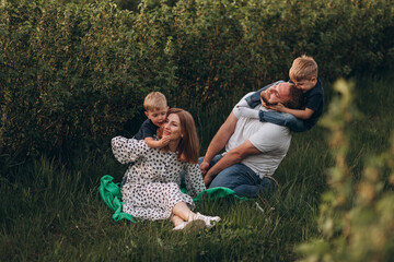 Big young happy family in the field on the nature. Mom, dad and 2 sons are having fun, running, fooling around together. Happiness and smiles around