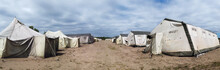 Old Soldiers Canvas Tents Torn In The Wind In The Field. Tent City On Military Exercises