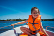 little girl in a swimming vest sits in a motorboat 