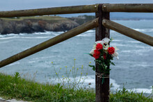 Bunch Of Red And White Roses Tied To A Fence Overlooking The Atlantic Ocean In Memory Of A Surfing Death