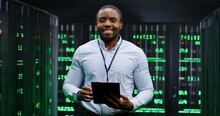 Portrait Of Young Handsome African American Man Smiling Cheerfully Too Camera In Database Center Full Of Computers And Servers. Close Up Of Male Worker Of Server Room. Cybersecurity World.