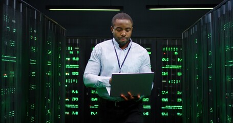 male african american big data analytic walking at server dark room, working with secret data and us
