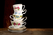 Stack Of Various English Vintage Porcelain Teacups With Floral Decoration On Dark Background.
