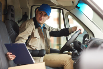 Delivery person checking the address of delivery while driving the van