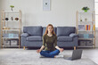 © Studio Romantic - Calm girl meditating or doing yoga to online video tutorial. Woman practicing breathing or relaxation exercises at home
