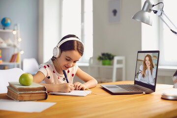 School girl online learning. Girl in casual clothes watching video chat teacher lecture has laptop sitting at table at home