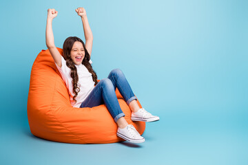 Portrait of nice attractive cheerful cheery excited glad wavy-haired girl sitting in chair rejoicing win winner having fun isolated on bright vivid shine vibrant blue teal turquoise color background