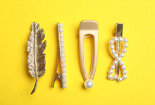 Stylish hair clips on yellow background, flat lay