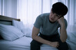 © ronnarong - Stressed Asian young man sitting alone on bed. Bad relationship or bankrupt problem and sickness concept.