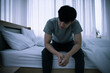 © ronnarong - Stressed Asian young man sitting alone on bed. Bad relationship or bankrupt problem and sickness concept.