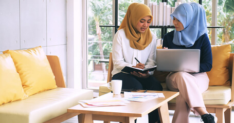 Two young muslim businesswomen discussing a work in the office.