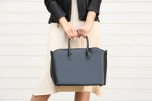Young Woman With Stylish Leather Bag Near White Wall, Closeup