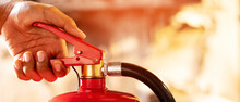 Hand Presses The Trigger Fire Extinguisher Available In Fire Emergencies Conflagration Damage Background. Safety
