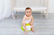© Any Grant - small baby girl 8 months old sitting on a potty, baby toilet, place for text