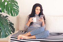 Woman With Phone And Coffee On Couch
