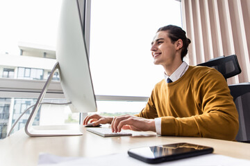 Smiling young man freelancer using laptop studying online working from home.