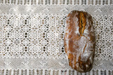 Fototapeta Lawenda - Frisches Sauerteigbrot auf einem Tisch mit Häkeldecke und einer Vase