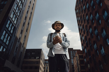 hiker man in a hat travels around city with a backpack. traveler stopped to write a message on his s