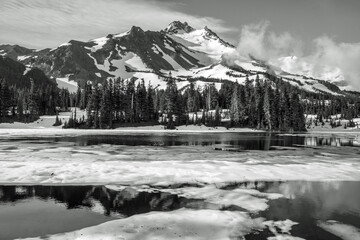 Wall Mural - volcanic mountain peak rises behind a partially thawed lake. calm water between patches of ice in th