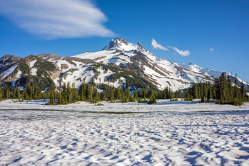 Wall Mural - volcanic mountain peak under a crisp blue sky rises behind a field of snow.