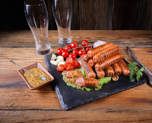 fried sausages, cherry tomatoes, garlic, dill, two empty beer glasses, mustard sauce, fresh herbs on a wooden table, rustic style