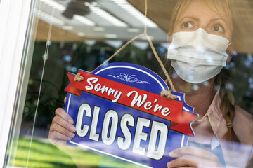 Wall Mural - Female Store Owner Wearing Medical Face Mask Turning Sign to Closed in Window