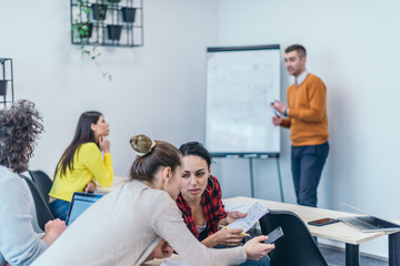 Wall Mural -  Multi-ethnic business group listening to a speaker while attending a business seminar at a modern workshop...