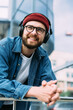 © mykolastock - Closeup vertical portrait of happy cheerful bearded handsome male hipster enjoying music in headphones in the city