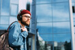© mykolastock - Serious modern young hipster traveler in headphones walks in the city
