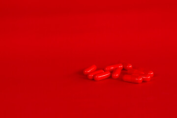 Wall Mural - Pills of red color on a neutral red background. Legal drugs from the pharmaceutical industry. Medications for human use