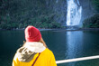 © Sheryl - A female tourist on a cruise boat watching a beautiful waterfall in Milford Sound, New Zealand