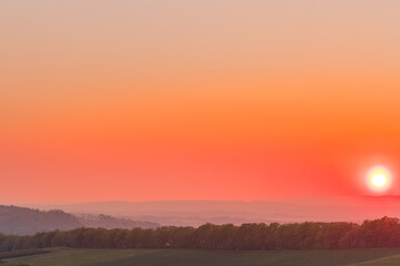 Sticker - The setting sun over the forested mountain landscape of the Beskydy region, the sun sets beyond the horizon.