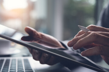 close up of man hand holding and using digital tablet online working from home