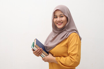 Wall Mural - Portrait of young muslim business woman wearing hijab holding book and smiling, educational or leisure activity concept