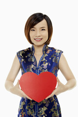 Woman in traditional clothing holding up a red heart