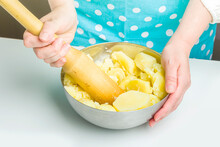 Cooking Potato Pie Fillings (quiche, Dumplings). Female Hands Hold A Wooden Potato Masher In The Home Kitchen. Close Up, Selective Focus, Backlight
