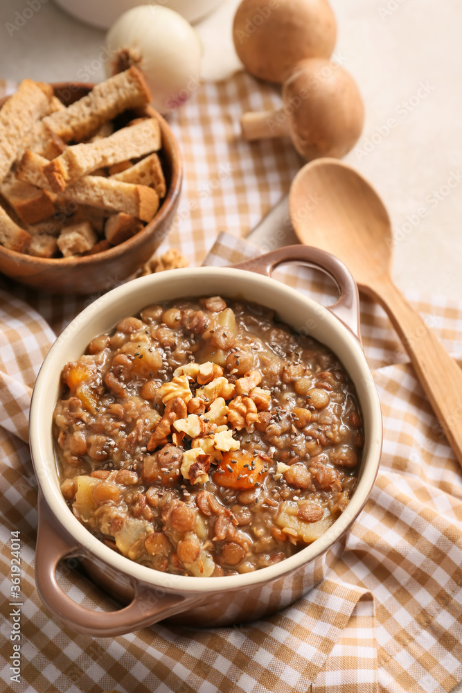 Pot of tasty lentils soup on table