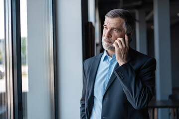 Poster - Senior business man talk on mobile phone at modern bright office interior.