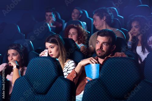 Group of people watching sad movie in cinema.