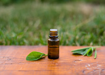 plantain oil in a glass bottle of dark glass on an old wooden background and leaves of fresh plantain