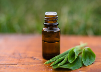 plantain oil in a glass bottle of dark glass on an old wooden background and leaves of fresh plantain