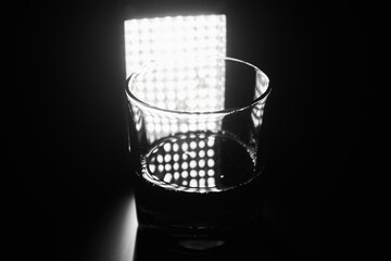 Black and white photo of empty glass on a matte black background with backlight