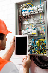 Canvas Print - Selective focus of electrician holding digital tablet with blank screen near electrical distribution box